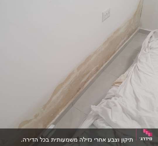 קיר עם סימני רטיבות ליד מיטה